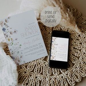 May include: A baby shower invitation with a floral design in shades of blue and white. The invitation is printed on a white background and features the text "Join us for a Baby Shower" in a gold script font. The invitation also includes the date, time, and location of the shower. The invitation is displayed on a phone screen and a white surface.