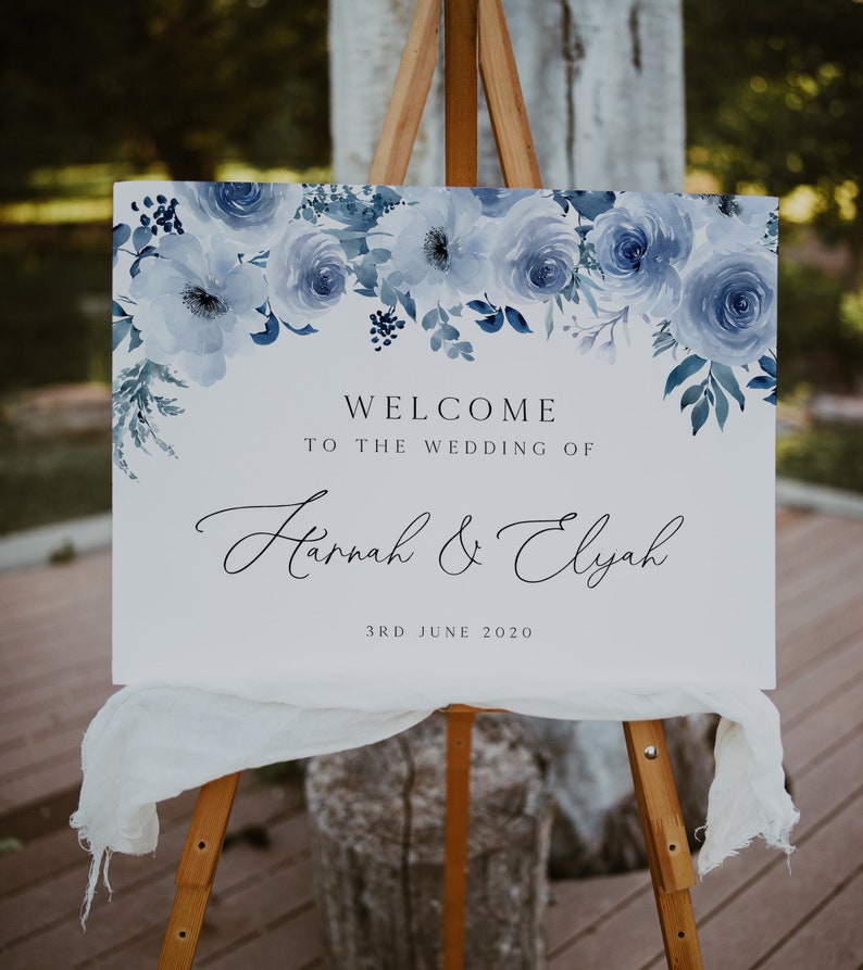 Puede incluir: Un cartel de bienvenida de boda blanco con dise&ntilde;os florales azules en acuarela. El cartel dice "Bienvenido a la boda de Hannah & Elyah 3 de junio de 2020".