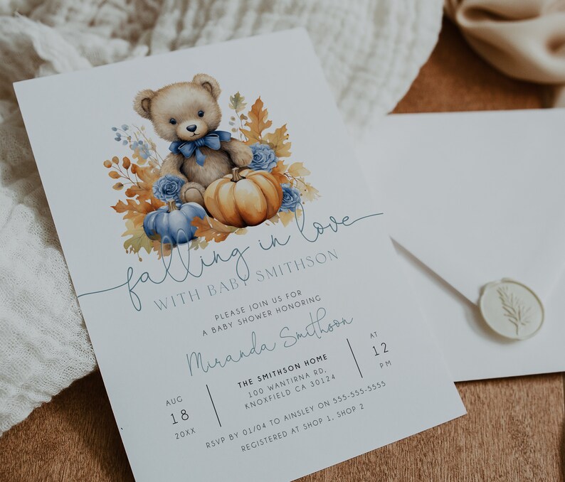 May include: A baby shower invitation featuring a watercolour illustration of a teddy bear holding a pumpkin, surrounded by autumn leaves and blue flowers. The text reads "falling in love with baby Smithson".