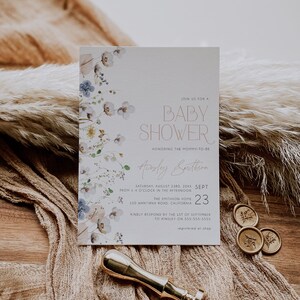 May include: A white baby shower invitation with a floral border. The invitation reads "Join us for a Baby Shower honoring the mommy-to-be Ainsley Smithson, Saturday, August 23rd, 20XX, from 1-4 o'clock in the afternoon, The Smithson Home, 100 Wantrina Road, California, Sept 23, Kindly respond by the 1st of September to Ainsley on 555-555-5555, registered at shop."