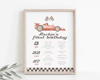 Może przedstawiać: Czerwony samochód wyścigowy z szachownicą na dachu. Tekst "Archie's first birthday" jest napisany brązowymi literami. Obrazek zawiera również listę kamieni milowych dla pierwszego roku życia dziecka, w tym liczbę zębów, funtów i cali.