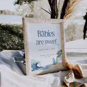 May include: A white framed sign with the text "Babies are sweet" in blue. The sign also includes the text "Please take a treat" and "Miranda's Baby Shower 03.04.20XX". The sign has a watercolor illustration of a wave, surfboards, and a palm tree.