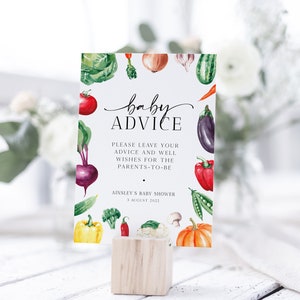 May include: A white card with a watercolor illustration of vegetables and the text "baby advice" in black script. The card also includes the text "Please leave your advice and well wishes for the parents-to-be" and "Ainsley's Baby Shower 3 August 2022".