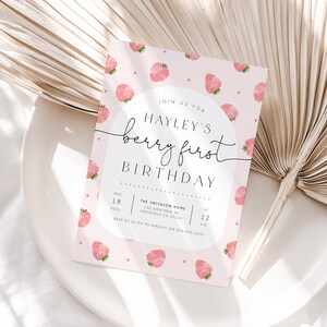 Op de afbeelding: Roze verjaardagsuitnodiging met een aquarelpatroon van aardbeien. De uitnodiging luidt "Join us for Hayley's Berry First Birthday" met de datum en tijd van het feest.