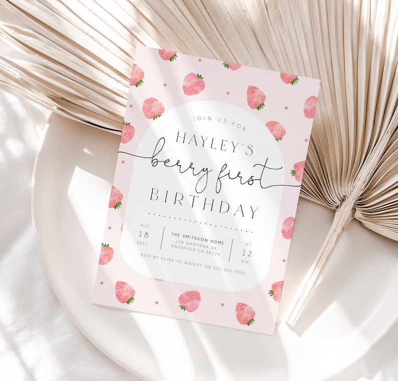 Op de afbeelding: Roze verjaardagsuitnodiging met een aquarelpatroon van aardbeien. De uitnodiging luidt "Join us for Hayley's Berry First Birthday" met de datum en tijd van het feest.