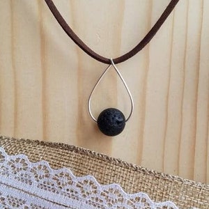 May include: A brown leather cord necklace with a silver teardrop pendant and a black lava rock bead.