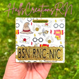 May include: A white badge holder with a gold glitter nameplate that reads "BSN RNC-NIC". The badge holder has a pattern of Harry Potter-themed illustrations, including a sorting hat, glasses, and a golden snitch.