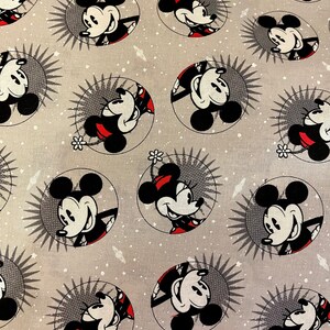 May include: A gray fabric with a repeating pattern of Mickey Mouse in a circle. The background is a light gray with white speckles. Mickey Mouse is wearing red shorts and yellow shoes.
