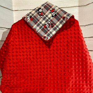 May include: Red minky baby blanket with a plaid fabric panel featuring Mickey Mouse and Minnie Mouse characters. The panel is attached to the blanket with a decorative stitch.