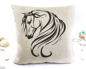 May include: A beige linen pillow with a black silhouette of a horse's head and mane. The horse's head is facing to the left, and the mane is flowing behind it.