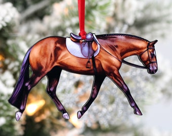 May include: A brown horse with a saddle and bridle, depicted in a walking pose. The horse is a Christmas ornament made of metal and has a red ribbon attached to the top.