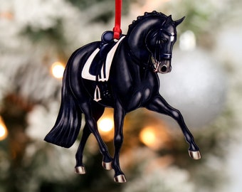 Può includere: Ciondolo natalizio a forma di cavallo nero con sella e briglia bianche. Il cavallo è in una posa di dressage con le gambe estese.