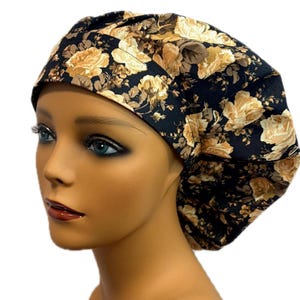 May include: A floral print scrub cap featuring a black background with large cream and tan roses. The cap is designed to cover the head and hair, commonly used in medical or culinary settings. The fabric appears to be cotton or a similar material.