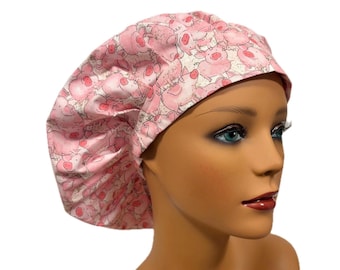 May include: A scrub cap featuring a repeating pattern of pink cartoon pigs on a light background. The cap has a gathered, rounded crown design with a wide band that fits securely around the head, showcasing a whimsical pig print.
