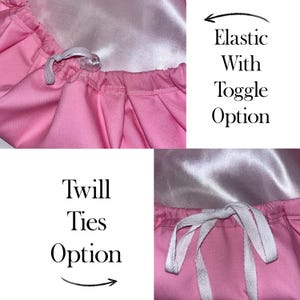 May include: A pink bonnet with a smooth light pink interior lining. The top section shows an elastic band with a clear plastic toggle. The bottom section displays a pair of white twill ties. Text on the image reads Elastic With Toggle Option and Twill Ties Option.