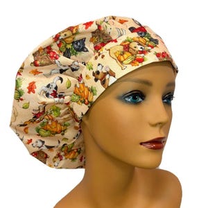 May include: A beige scrub cap featuring a repeating pattern of various dog breeds, pumpkins, and autumn leaves. The hat has a gathered, rounded crown and a wide, structured band that sits across the forehead, showcasing the colorful fall-themed print.