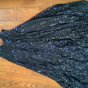 May include: A black sequined dress with thin straps. The dress is made of a soft, flowing fabric and has a loose, flowing fit.