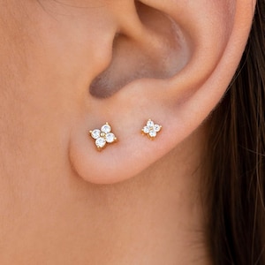 Puede incluir: Un par de pendientes de oro en forma de flor con piedras de circonita c&uacute;bica transparentes.