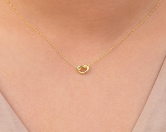 Puede incluir: Un collar de cadena de oro con un colgante simple anudado.
