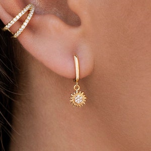Huggie hoop earrings with sun-shaped pendant and cubic zirconia