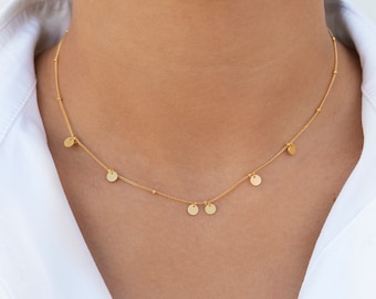 May include: A gold necklace with small, round charms hanging from it. The necklace is delicate and dainty, and would make a great gift for a friend or loved one.