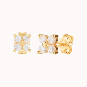 Puede incluir: Un par de pendientes de bot&oacute;n de oro con un dise&ntilde;o de flor con piedras de circonita c&uacute;bica transparentes.