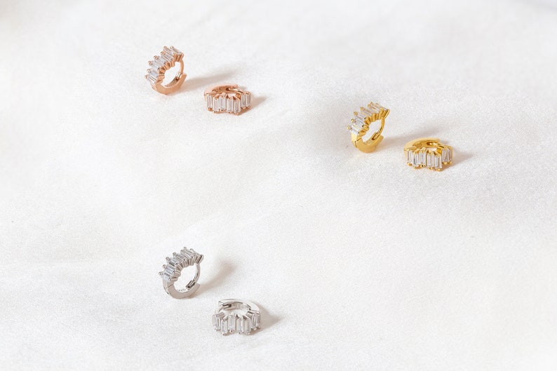 K&ouml;nnte beinhalten: F&uuml;nf Paar Creolen mit einer Reihe von baguettef&ouml;rmigen Zirkonia-Steinen. Die Ohrringe sind in Silber, Gold und Ros&eacute;gold erh&auml;ltlich.