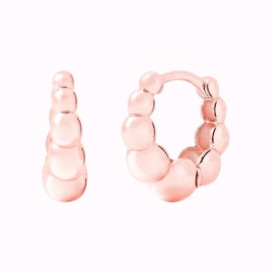 Pu&ograve; includere: Un paio di orecchini a cerchio in oro rosa con un design a perline. Gli orecchini sono realizzati con piccole perline rotonde che sono collegate tra loro per formare una forma a cerchio.