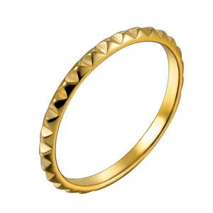 May include: A gold-coloured ring with a textured band. The band is decorated with a series of small, triangular shapes.