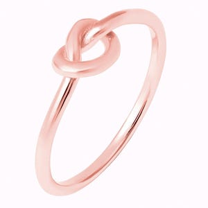 Puede incluir: Un anillo de nudo de oro rosa. El anillo es simple y elegante, con un acabado liso.