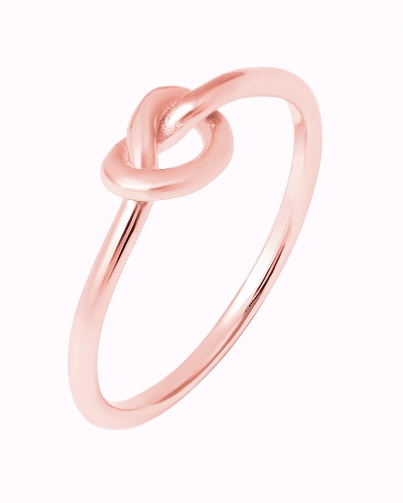 Puede incluir: Un anillo de nudo de oro rosa. El anillo es simple y elegante, con un acabado liso.