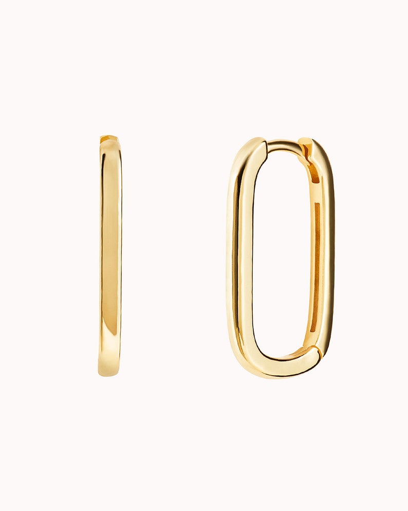 May include: A pair of gold-toned hoop earrings with a rectangular shape. The earrings are made of a smooth metal and have a polished finish.