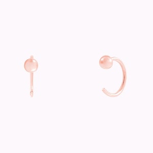 Puede incluir: Un par de pendientes de aro de oro rosa con una peque&ntilde;a bola al final de cada aro.