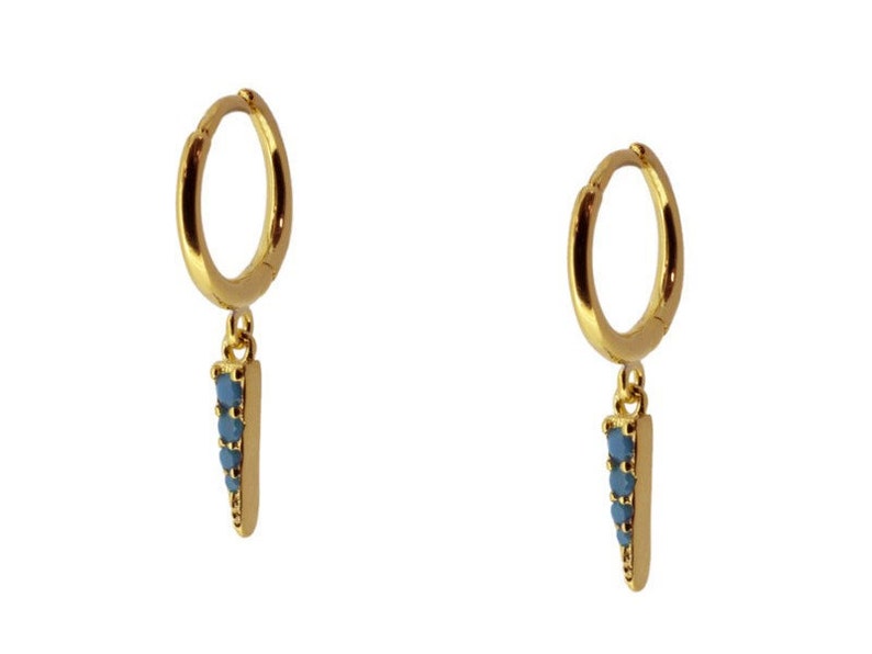 K&ouml;nnte beinhalten: Goldene Creolen mit einem baumelnden blauen Edelstein-Spitzenanh&auml;nger.