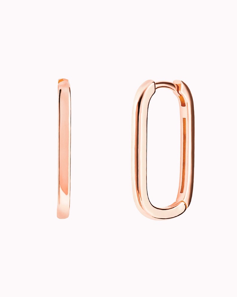 May include: A pair of rose gold hoop earrings with a rectangular shape.