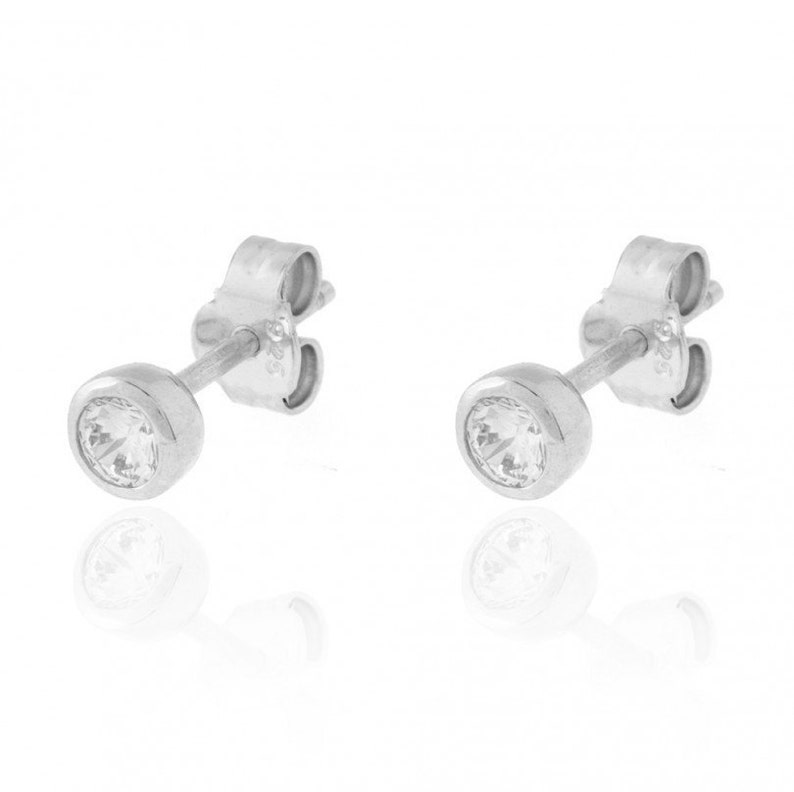 May include: A pair of silver stud earrings with clear round stones.