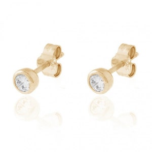 May include: A pair of gold stud earrings with a clear round stone in the center.