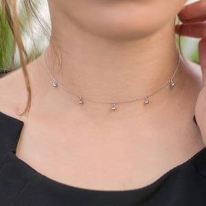 May include: A silver choker necklace with small round charms hanging from it.