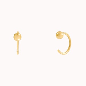 Puede incluir: Un par de pendientes de aro de oro con una peque&ntilde;a bola en el extremo de cada aro.