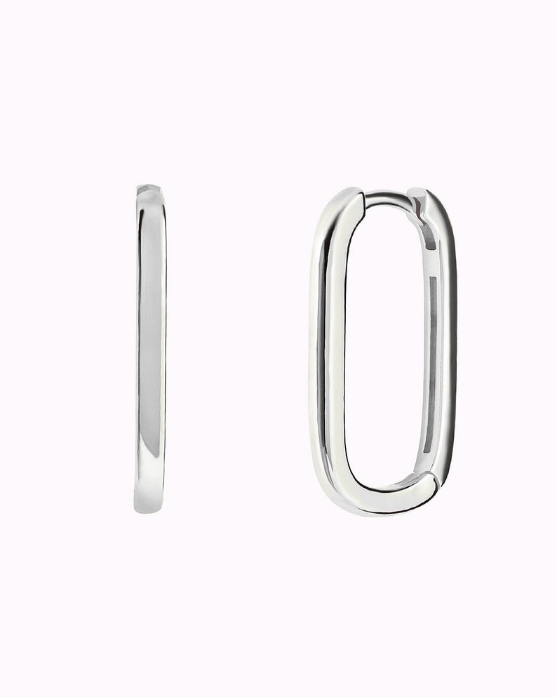 May include: A pair of silver hoop earrings with a rectangular shape.