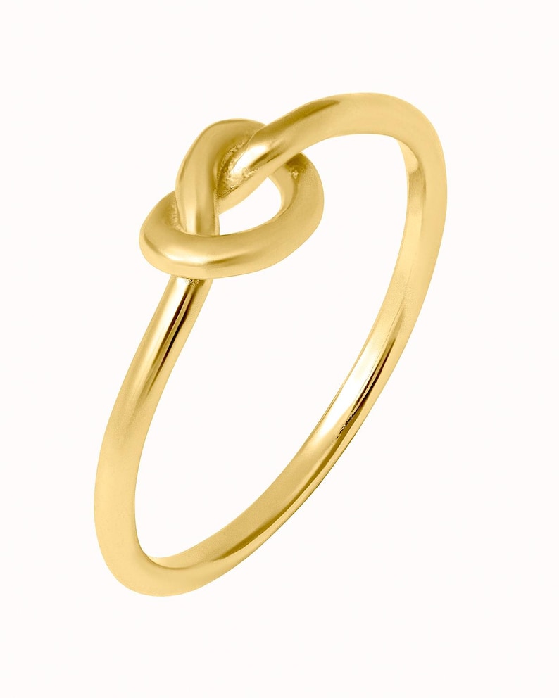 Puede incluir: Un anillo de nudo dorado con un dise&ntilde;o sencillo. El anillo est&aacute; hecho de metal liso y pulido y tiene un aspecto cl&aacute;sico y atemporal.