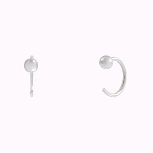 Puede incluir: Un par de pendientes de aro de plata con una peque&ntilde;a bola redonda en el extremo de cada aro.