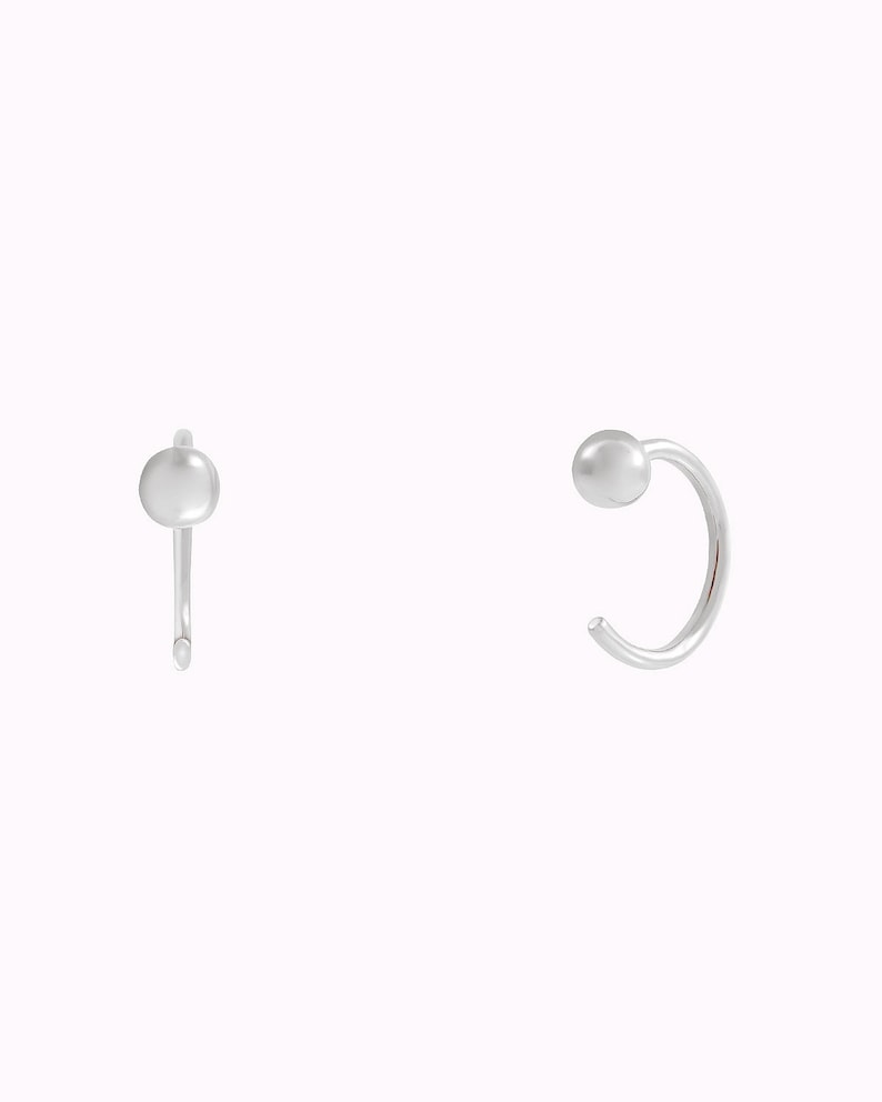 Puede incluir: Un par de pendientes de aro de plata con una peque&ntilde;a bola redonda en el extremo de cada aro.