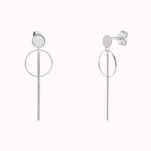 May include: A pair of silver earrings with a circle and a long, thin rod hanging from a small round disc.