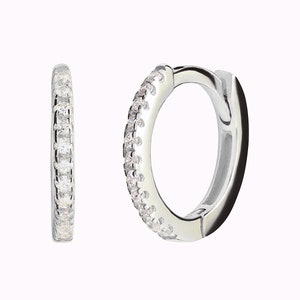 May include: A pair of silver hoop earrings with a row of small clear cubic zirconia stones around the edge.