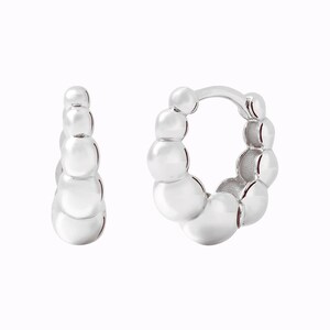 Pu&ograve; includere: Un paio di orecchini a cerchio d'argento con un design a perline. Gli orecchini sono realizzati con piccole perline rotonde che sono collegate tra loro per formare una forma a cerchio.