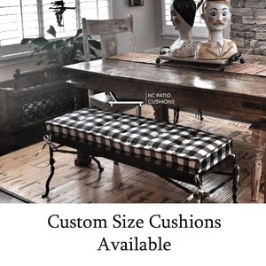 May include: Black and white checkered bench cushion with a wooden frame. The cushion is on a wooden floor with a woven mat underneath. The text "NC Patio Cushions" is visible in the image.