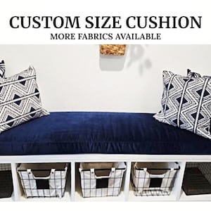 May include: A navy blue bench cushion with two black and white geometric patterned throw pillows. The bench is part of a white bench with three storage baskets underneath. The text "CUSTOM SIZE CUSHION MORE FABRICS AVAILABLE" is at the top of the image.