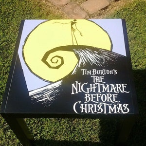 Könnte beinhalten: Schwarzer quadratischer Couchtisch mit einer Grafik von Jack Skellington aus dem Film "Nightmare Before Christmas" auf der Oberseite. Die Grafik ist in Schwarzweiß mit einem gelben Mond und einem violetten Himmel.
