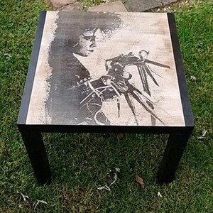 May include: Black and white image of a character from the film Beetlejuice on a square coffee table with black legs.